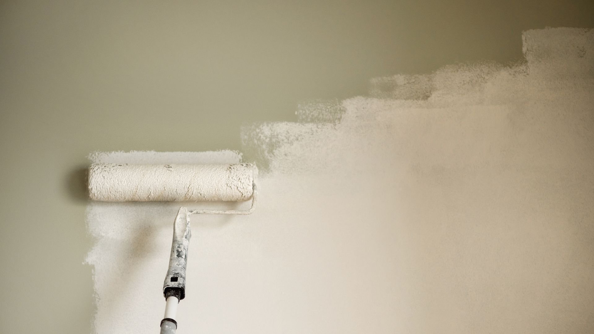Paint roller painting a wall white during home renovation