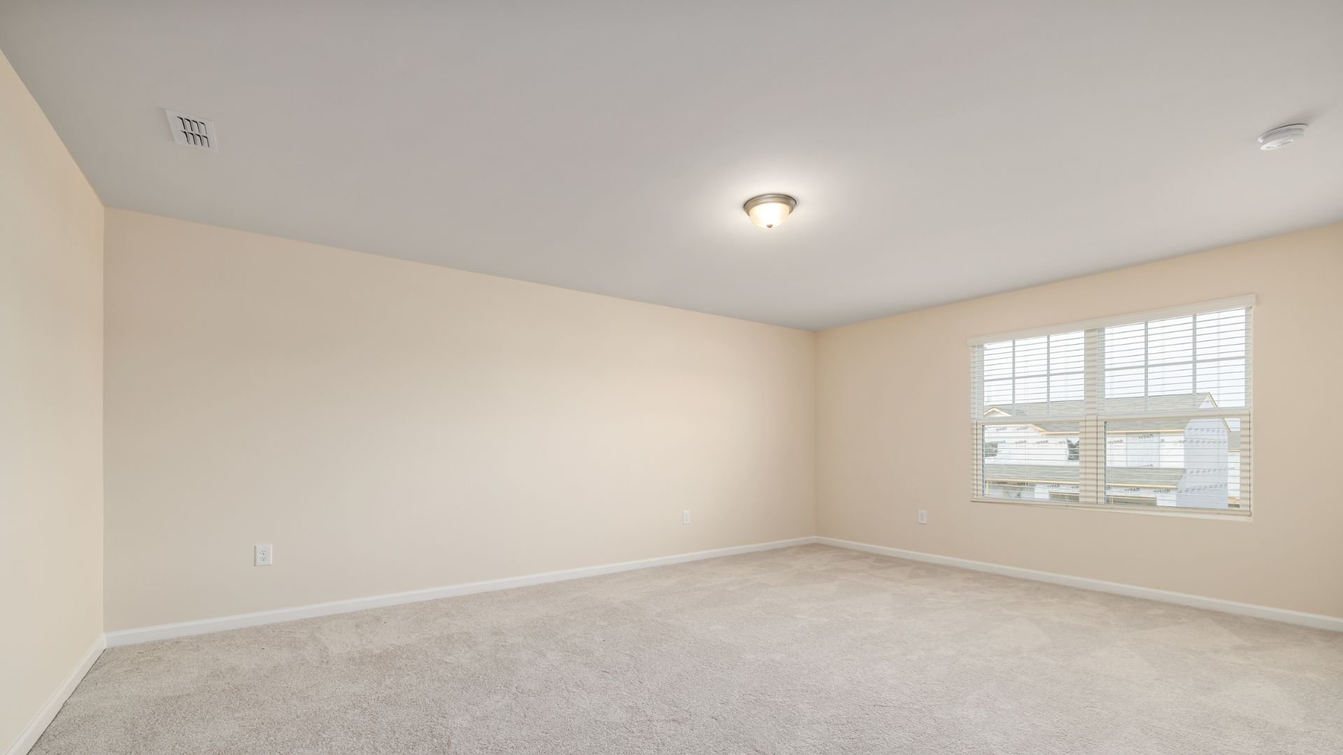 Empty room with beige walls, carpet, and window with white blinds