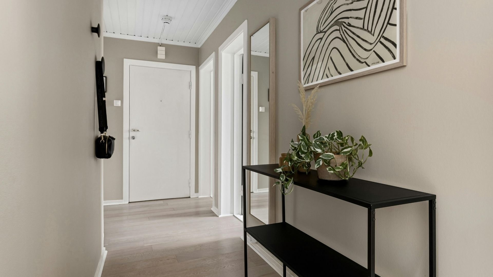 Minimalist entryway with white door, black console, and abstract wall art