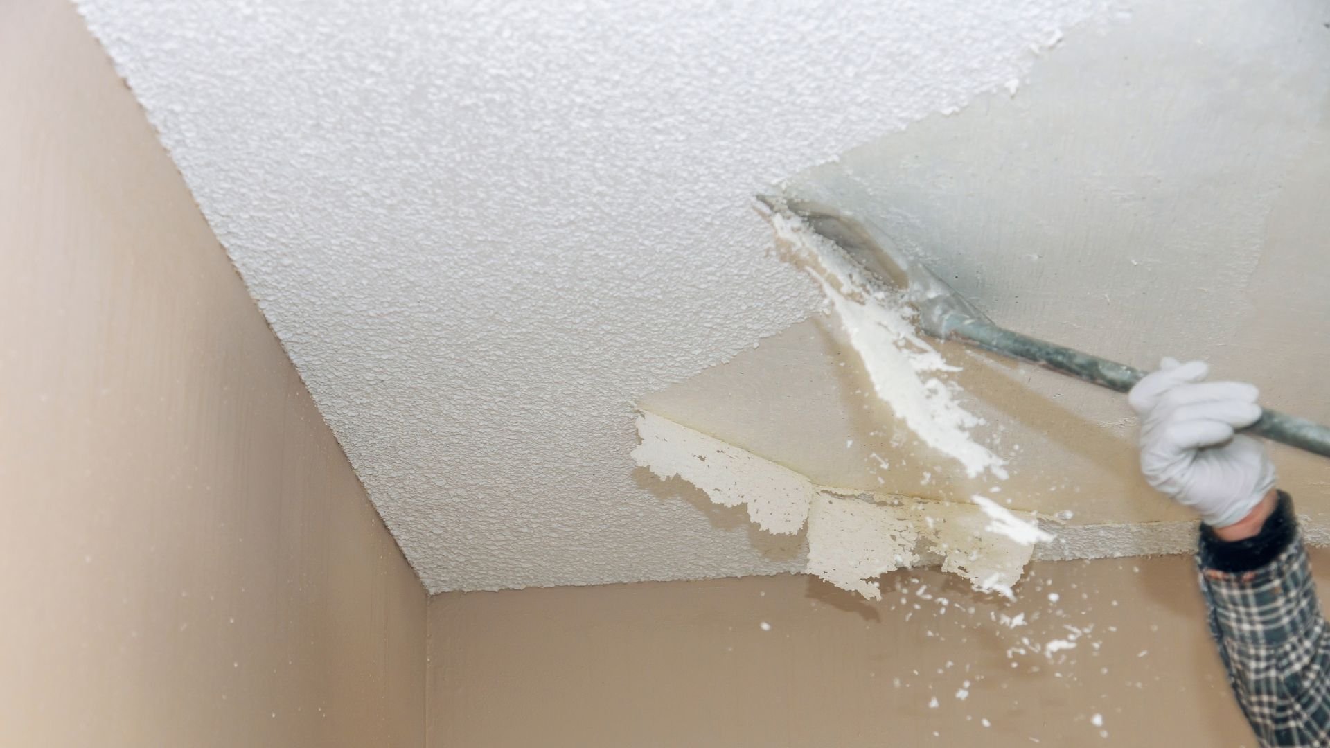 Person scraping textured ceiling during home renovation or repair