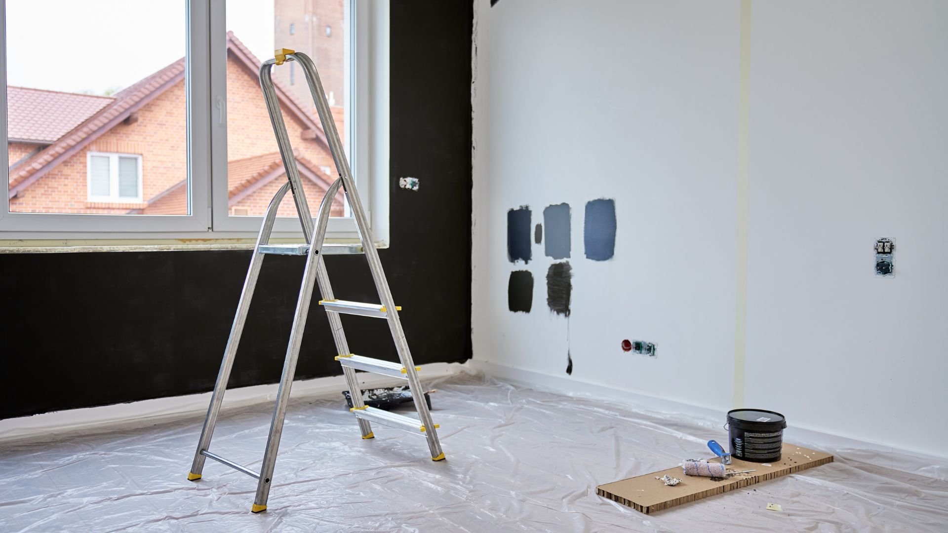 Room interior with ladder, paint samples, and drop cloth during renovation
